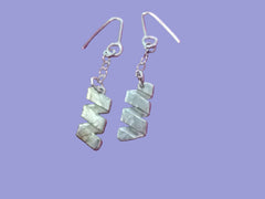 Silver zigzag earrings on a purple textured background